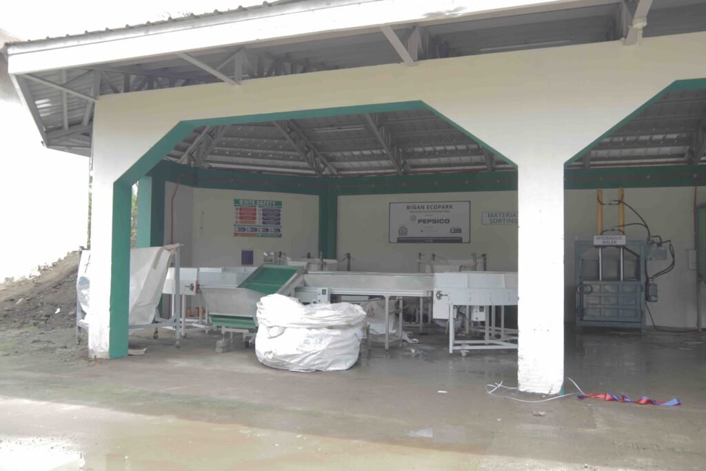 The Enhanced Materials Recovery Facility showcases its mechanized sorting lines and processing equipment, featuring the integrated government-supplied machinery that was previously underutilized, now repurposed to sort and process various types of plastic waste including shopping bags, sachets, and multilayered packaging.